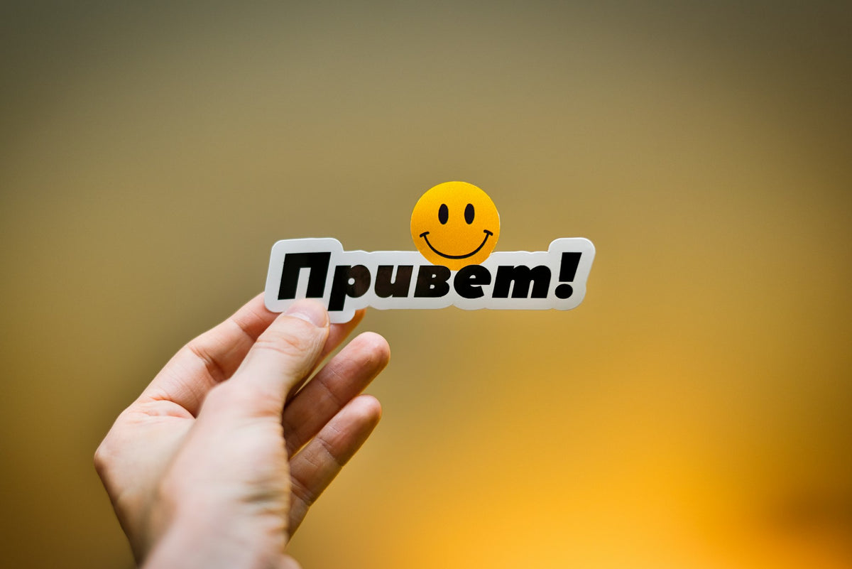 Hand holding a sticker with the Russian word привет